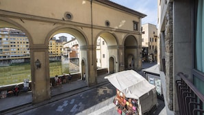 A narrow street with a row of arches and a small outdoor market stall. - Vasari Suite Florence (Florence)