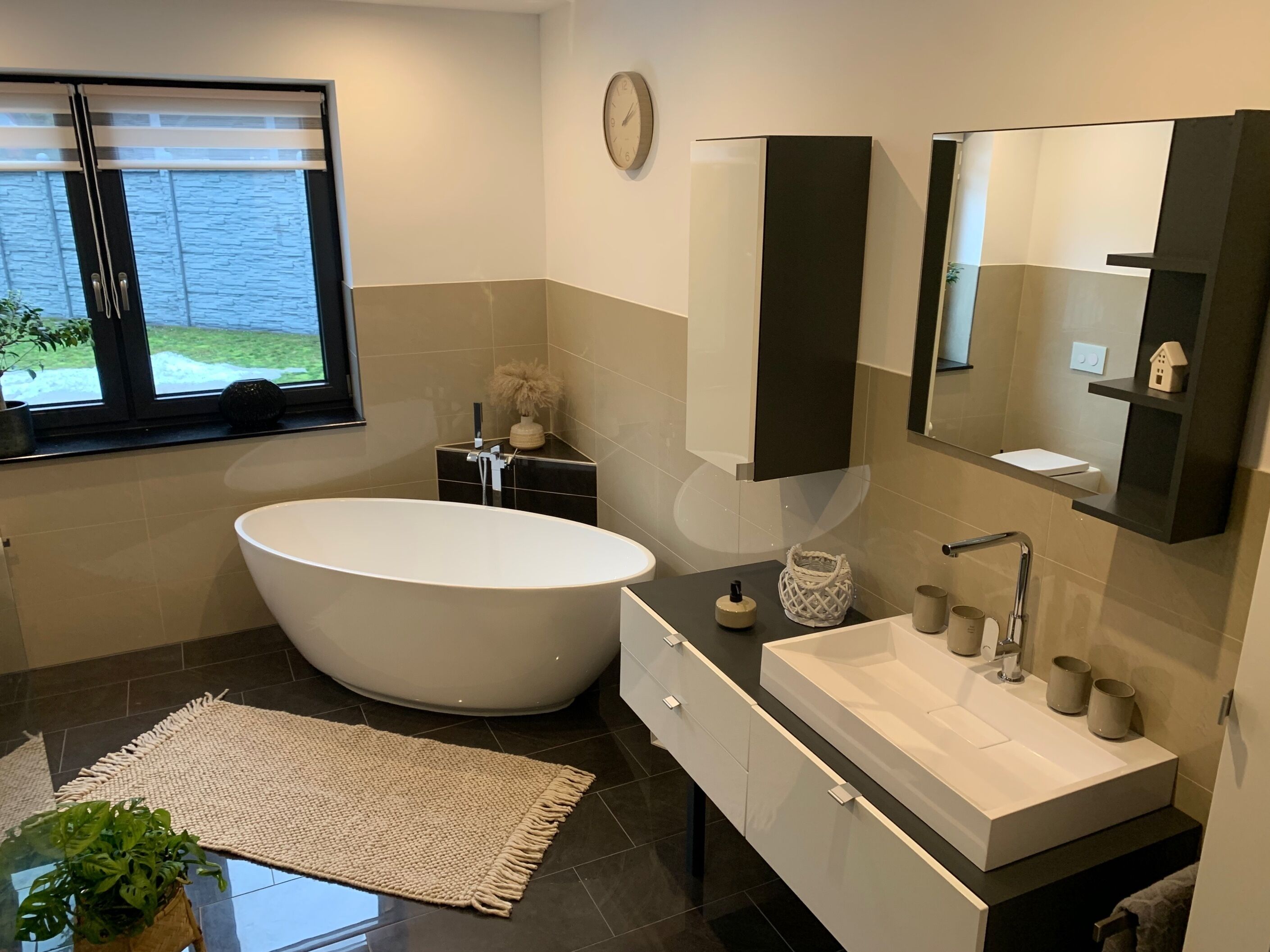 Une salle de bain moderne avec une baignoire sur pieds, un meuble-lavabo doté d’un grand évier et un miroir au-dessus de l’évier.