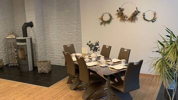 Un comedor con pared de piedra, chimenea y tres coronas decorativas colgadas en la pared.