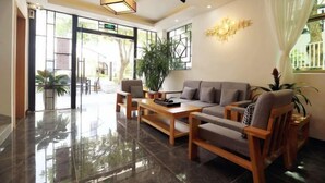 A modern lobby with a sofa, chairs, a coffee table, and a large plant. - Dongmenyuan Inn (Shenzhen)