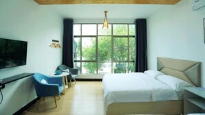 A hotel room with a bed, a TV, a desk, a chair, and large windows. - Dongmenyuan Inn (Shenzhen)