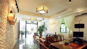 A hotel lobby with a brick wall, wooden furniture, and a large window with curtains. - Dongmenyuan Inn (Shenzhen)