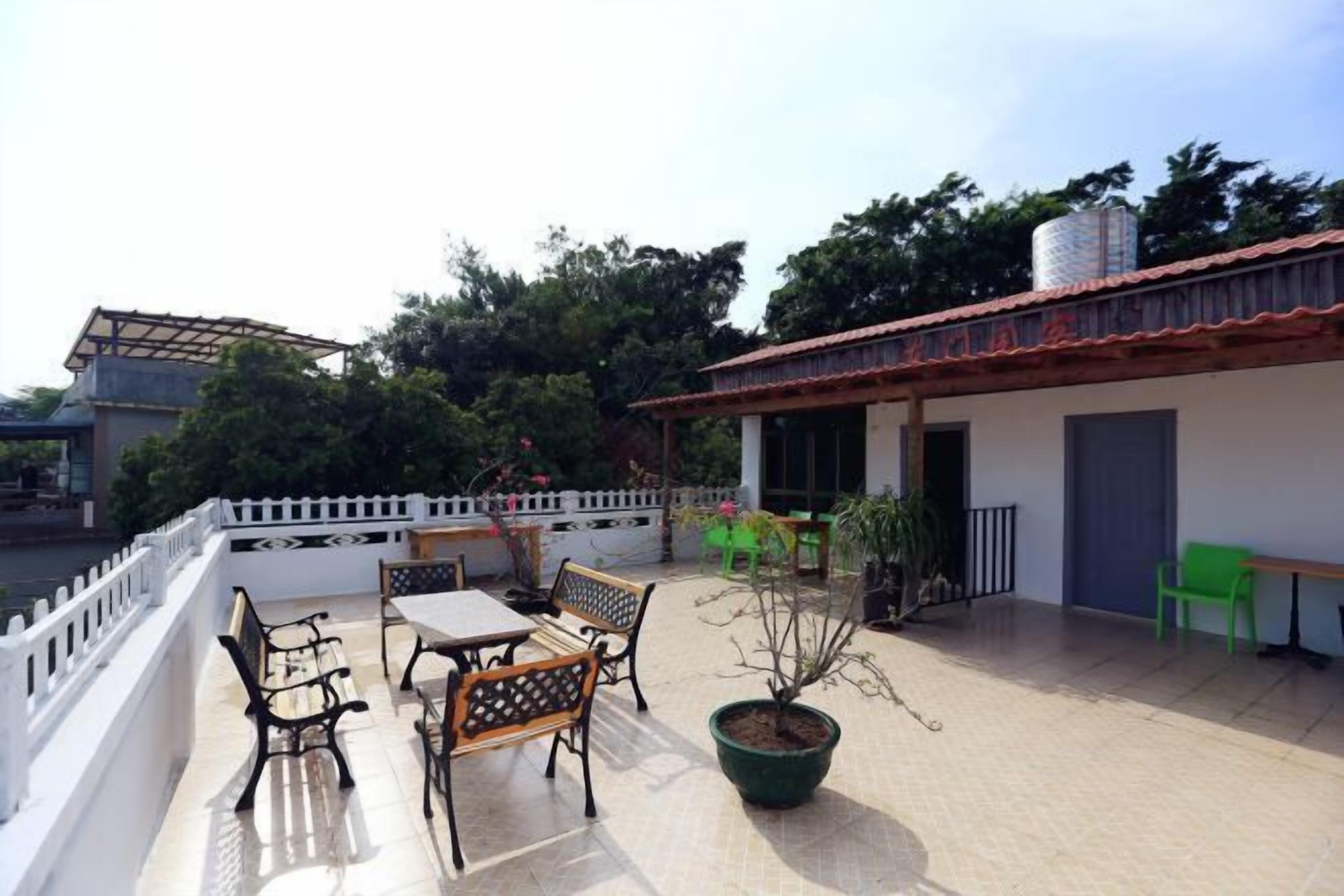 Una terraza con mobiliario exterior, una planta en maceta y un edificio con tejado de baldosas.
