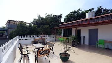 Una terraza con mobiliario exterior, una planta en maceta y un edificio con tejado de baldosas.