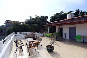 A terrace with outdoor furniture, a potted plant, and a building with a tiled roof. - Dongmenyuan Inn (Shenzhen)