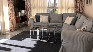 Ein Wohnzimmer mit einem gestreiften Sofa, einem Couchtisch und einem Fernseher auf einem Schrank.
