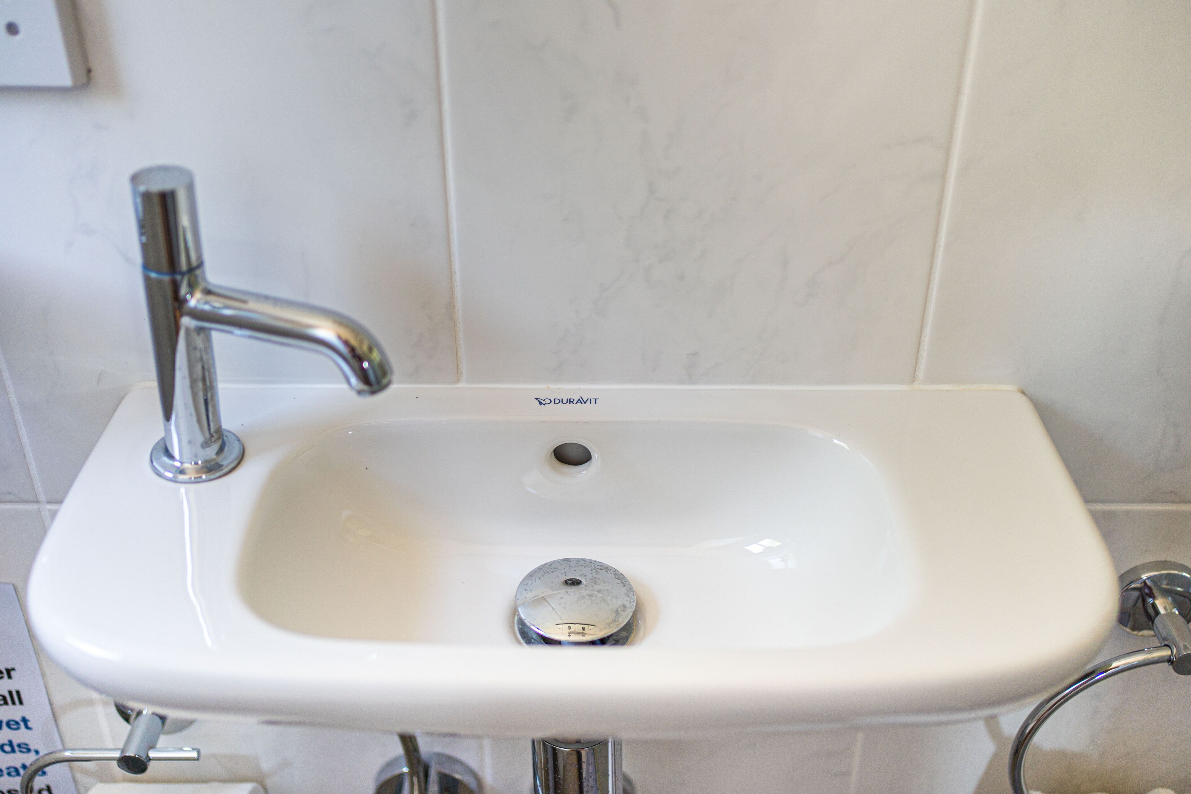 Un lavabo de salle de bain blanc, doté d’un robinet chromé et d’un bouchon de vidange.