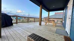A wooden deck with a covered area, a picnic table, and a barbecue grill. - Blue Haven Beach!! (Freeport)