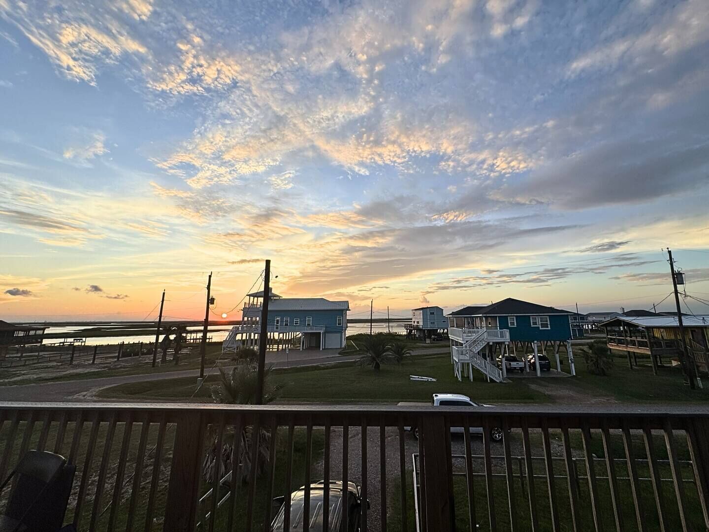 A coastal area with houses on stilts, a dock, and a sunset view.