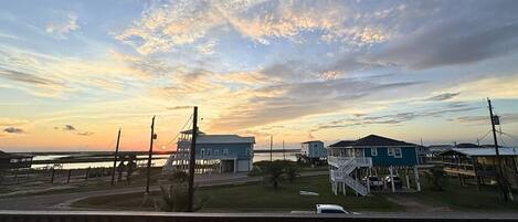 A coastal area with houses on stilts, a dock, and a sunset view.