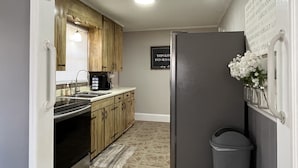 A compact kitchen with wooden cabinets, a stainless steel refrigerator, and a built-in oven. - Peaceful Place in Winston Salem (Winston-Salem)