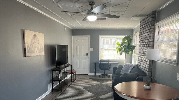A living room with a TV, a dining table, a sofa, a chair, a rug, and a ceiling fan. - Peaceful Place in Winston Salem (Winston-Salem)