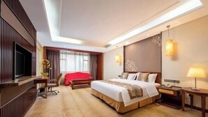 Ein Hotelzimmer mit einem großen Bett, einem Fernseher, einem Schreibtisch und einem roten Sessel.