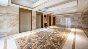 Ein geräumiger Korridor mit Marmorboden und goldenen Verzierungen an der Decke.