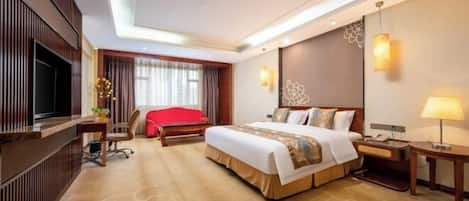 A hotel room with a large bed, a TV, a desk, and a red chair.