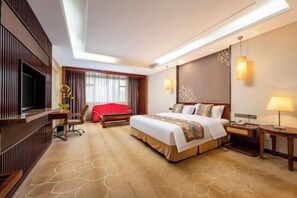 Ein Hotelzimmer mit einem großen Bett, einem Fernseher, einem Schreibtisch und einem roten Sessel.