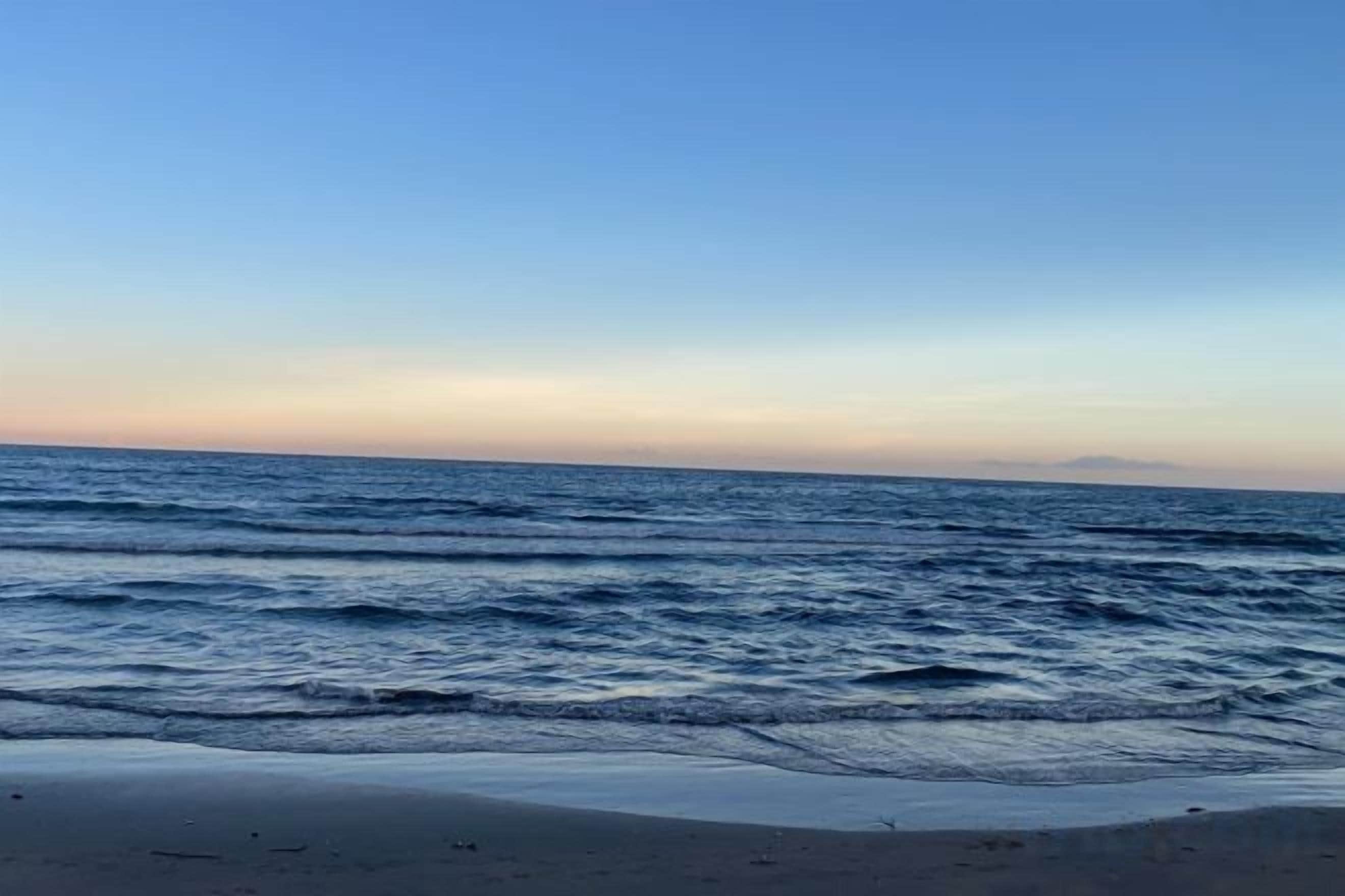 Une plage avec des vagues et un ciel dégagé.