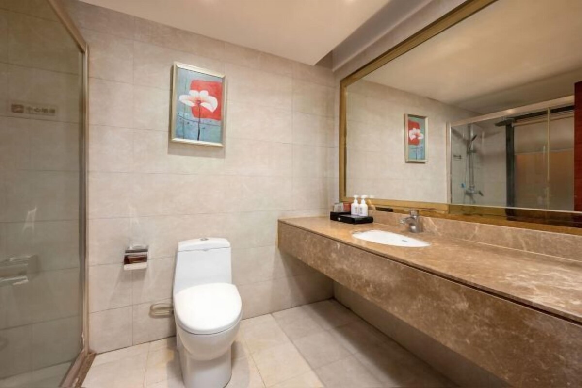 Ein Badezimmer mit Toilette, Waschbecken, einem großen Spiegel und einer Duschkabine.