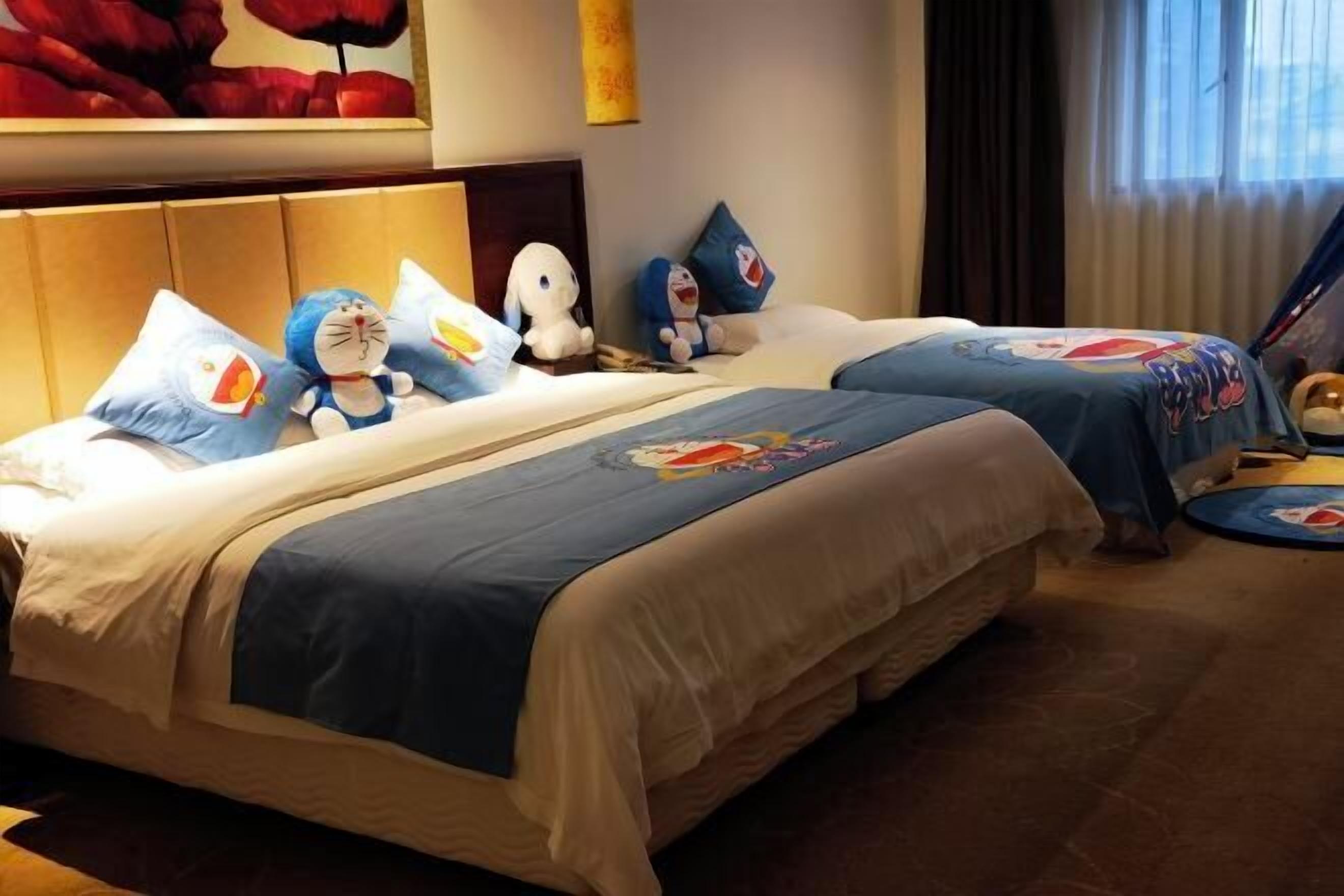 Quarto de hotel com duas camas, cada uma com colcha e almofadas estampadas com personagens de desenhos animados.