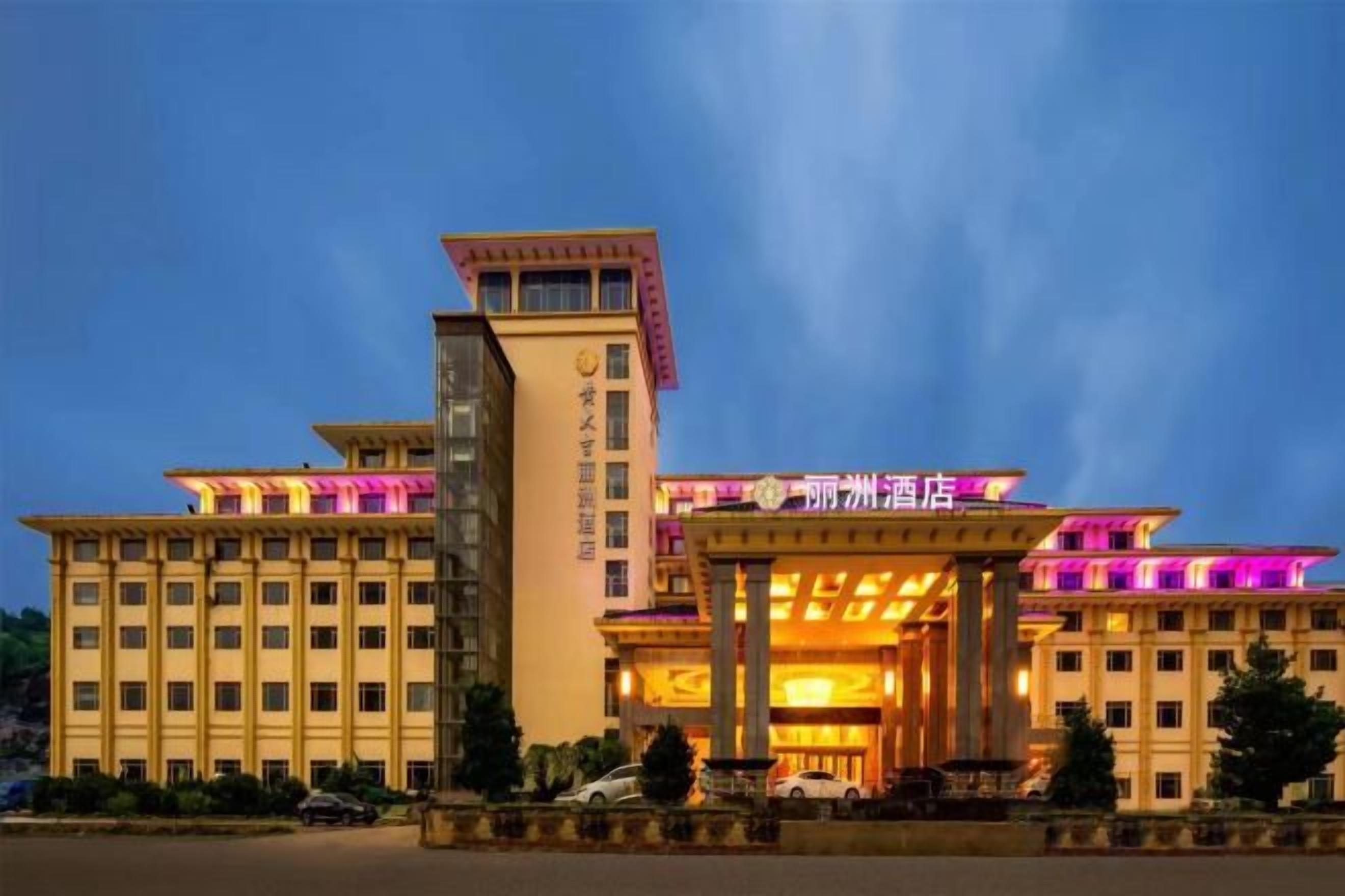 A multi-story hotel with a prominent entrance, a central tower, and a well-lit facade.