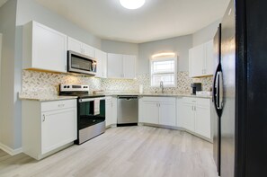 A modern kitchen with white cabinetry, a stainless steel microwave, an oven, and a dishwasher. - Walk to Dtwn Warrensburg: Cozy Family Home! (Warrensburg)