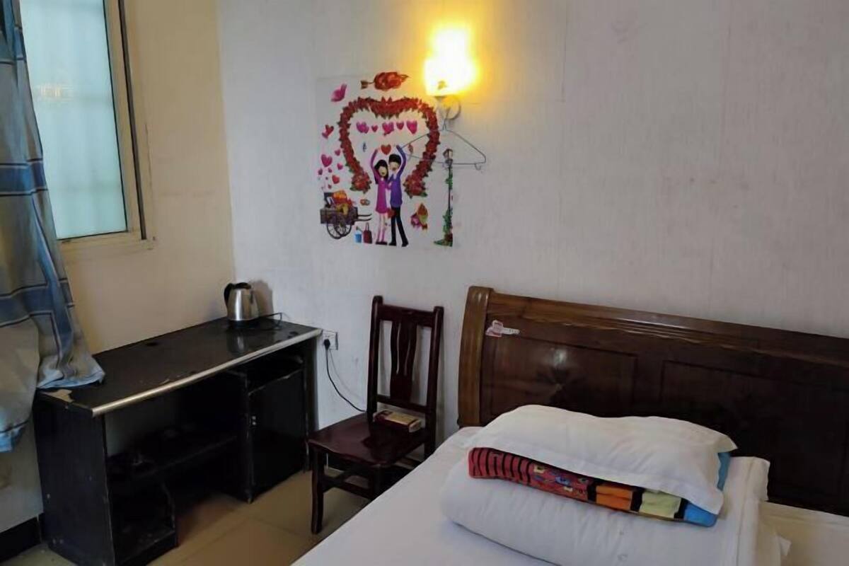 A room with a bed, a desk, and a chair. There is a wall decoration above the bed.