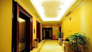 Un vestíbulo de hotel con suelo de mármol, puertas de madera y plantas en macetas.