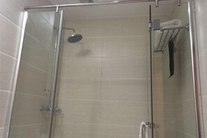 Shower area features a wall-mounted showerhead and towel rack.