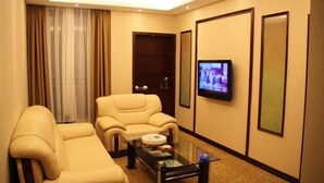 Una habitación de hotel con un sofá, televisión y una mesa de centro.