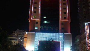 Un edificio de gran altura con franjas verticales iluminadas y una gran pantalla LED en la fachada.