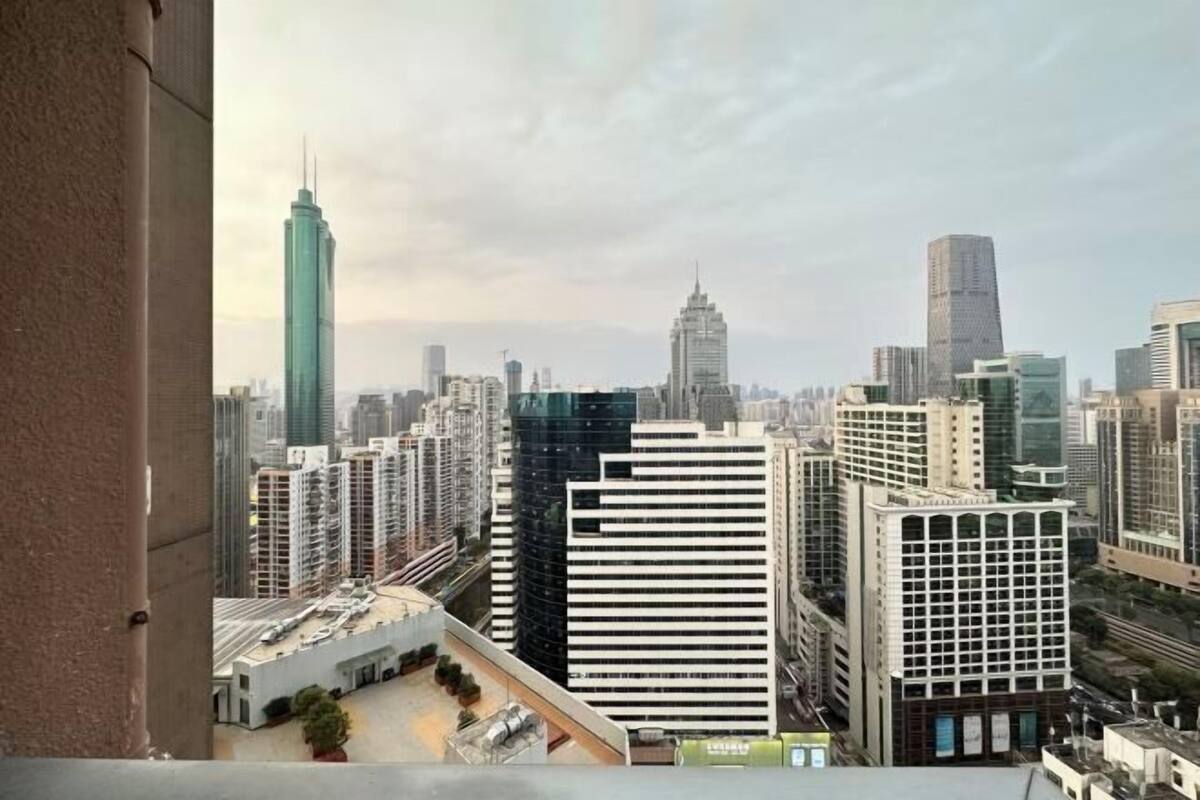 Un paysage urbain avec de hauts immeubles, dont un gratte-ciel imposant coiffé d’une flèche, et un mélange de styles architecturaux modernes et plus anciens.