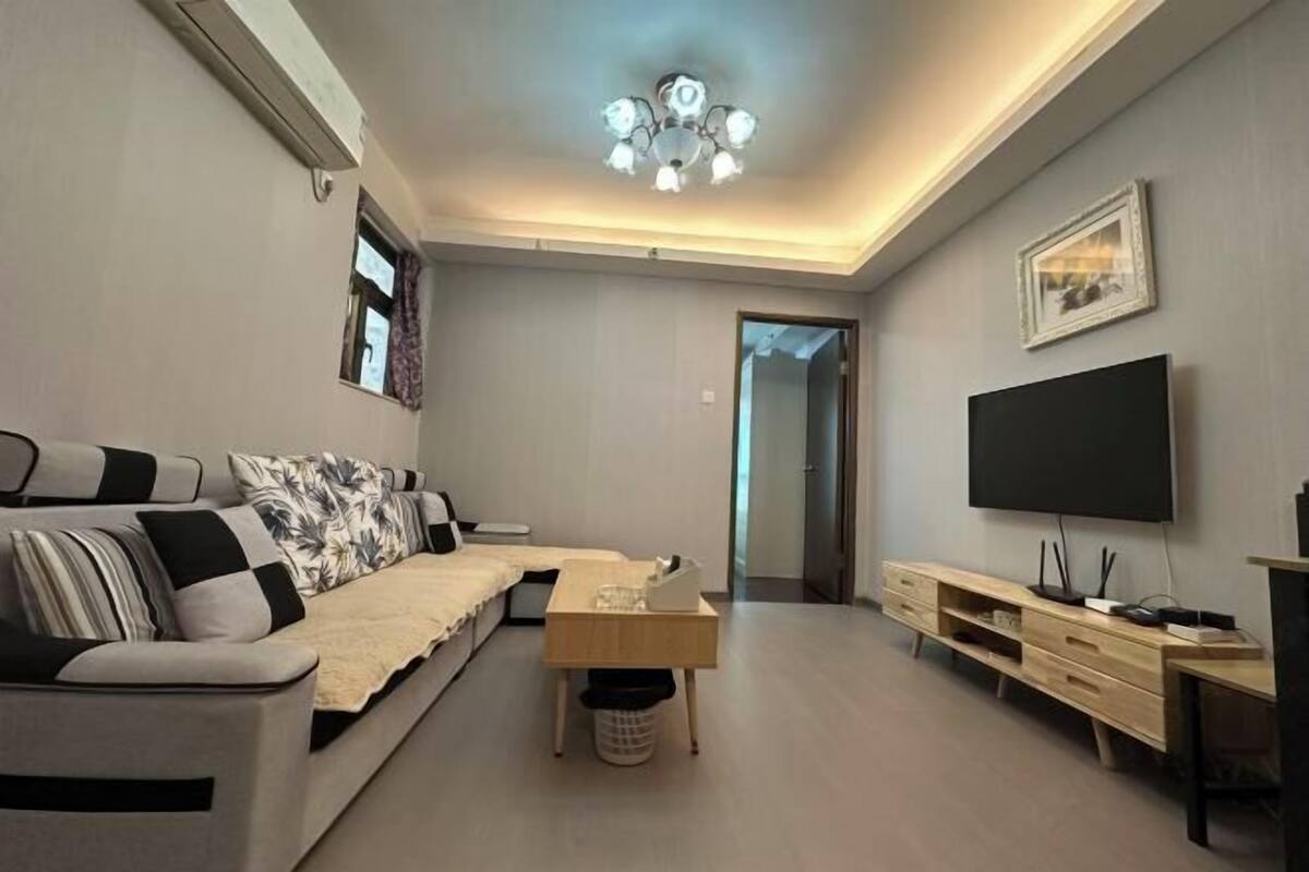 Un salon moderne comprenant un canapé, une table basse, un téléviseur et une petite table avec une poubelle.