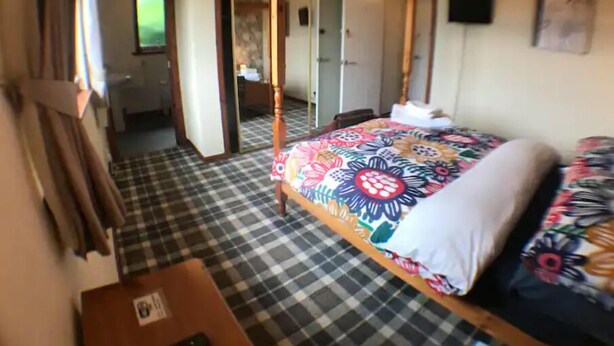 A room with a four-poster bed, checkered floor, and a door leading to a bathroom. - Fort William Central Self Catering House# (Fort William)