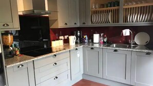 A kitchen with grey cabinets, a black stove, and a wooden floor. - Fort William Central Self Catering House# (Fort William)