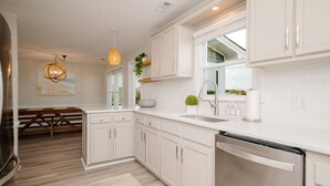 Una cocina moderna con muebles blancos, lavavajillas integrado y un amplio ventanal que proporciona luz natural.