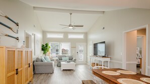 Un salón amplio con sofá, una mesita de centro y una mesa de comedor de madera con individuales.