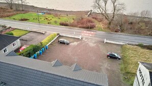 A hotel with a parking lot and a road in the background. - Etive, Beautiful Lochside Apartment with balcony (Fort William)