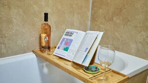 A wooden tray with a bottle, a magazine, and a glass on a bathtub. - Etive, Beautiful Lochside Apartment with balcony (Fort William)