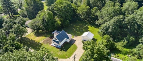 Set amidst lush greenery, this secluded property features a main house and attached structure, surrounded by a well-manicured lawn and driveway.
