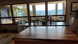 A dining area with a large wooden table and chairs, large windows with a view of trees and mountains, and a chalkboard with "Birthday" written on it. - HOT TUB'n at Shuswap Lake
RnR with MnM in our Pet-Friendly! Lakeview Home (Anglemont)