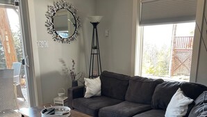 A living room with a dark grey sofa, a wooden coffee table, a floor lamp, and a decorative mirror. - HOT TUB'n at Shuswap Lake
RnR with MnM in our Pet-Friendly! Lakeview Home (Anglemont)