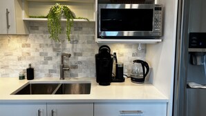 A modern kitchen with a stainless steel sink, a microwave, a coffee maker, and a refrigerator. - HOT TUB'n at Shuswap Lake
RnR with MnM in our Pet-Friendly! Lakeview Home (Anglemont)