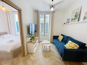 A modern room with a bed, a sofa, a TV, a small table, and a potted plant. - Cannes Meynadier Croisette, Palais Vieux Port 1 mn . 2 BR Olam Properties (Cannes)