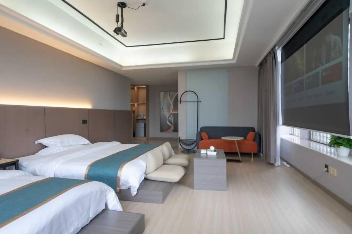Ein Hotelzimmer mit zwei Betten, einem Sofa, einem Couchtisch und einem großen Fenster.