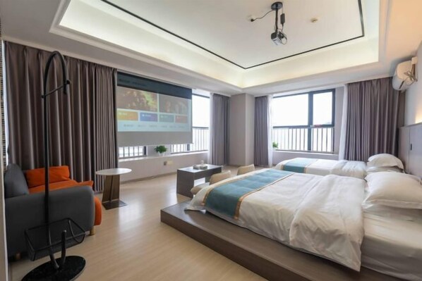 Une chambre d’hôtel avec un grand lit, un bureau, un canapé et un écran de télévision.