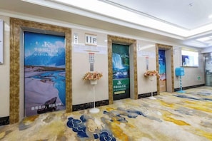 A hallway with doors, each with a poster and a small flower arrangement.