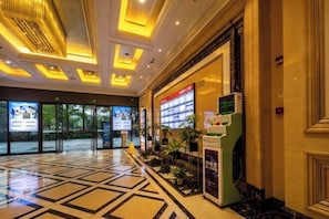 Un hall d’hôtel doté d’un sol à motifs géométriques, d’un comptoir d’accueil et d’une grande porte d’entrée en verre.