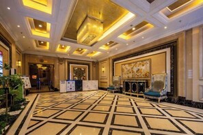 Un hall d’entrée spacieux, doté d’un sol à motifs, d’un comptoir de réception et d’un grand tableau accroché au mur.