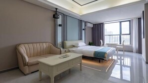 Une chambre d’hôtel moderne équipée d’un lit, d’un canapé, d’une table basse et d’une grande fenêtre.