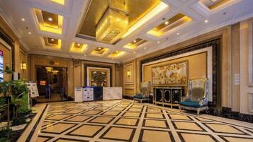 A hotel lobby with a patterned floor, a reception desk, and a seating area.